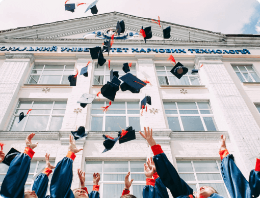graduation caps being thrown in front of a roman-esque building