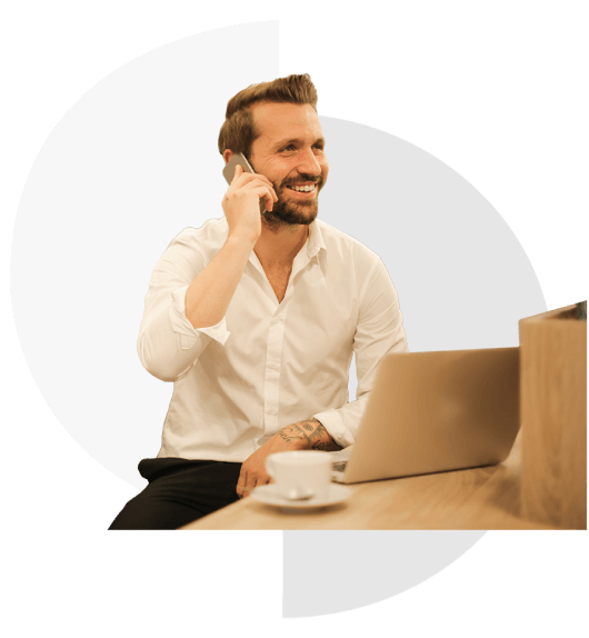 a happy man at a desk talking on the phone