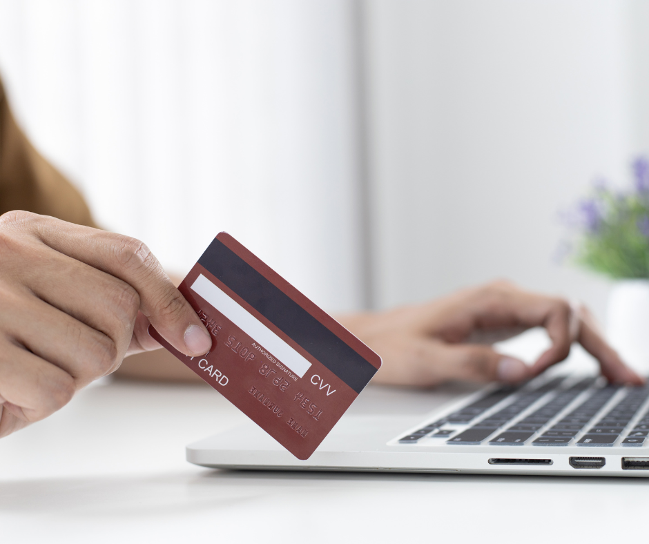 someone holding a credit card while looking at a laptop